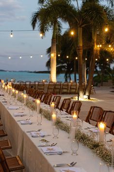 a long table is set up with candles and place settings for an outdoor wedding reception