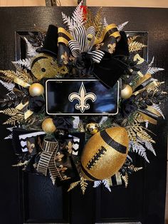 a new orleans saints wreath with footballs and christmas decorations on it, hanging from the front door