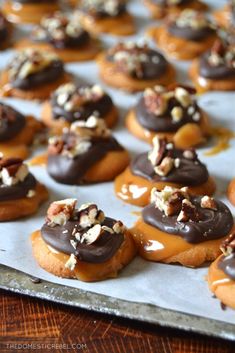 chocolate covered doughnuts with nuts and pecans on top are lined up on a baking sheet