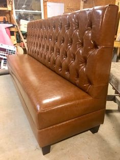 a brown leather couch sitting on top of a hard wood floor next to a wall