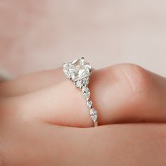 a woman's hand holding an engagement ring with a diamond on the top and side