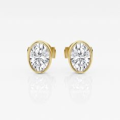 a pair of yellow gold earrings with a round brilliant diamond set in the center, on a white background