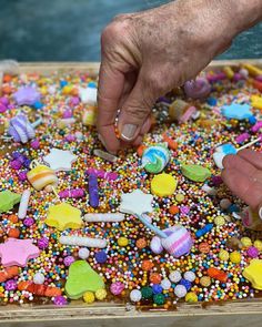 a person reaching for candy on a tray filled with sprinkles and candies