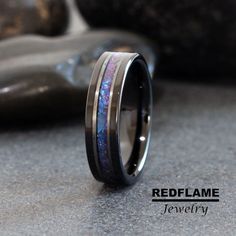 a wedding band with an opal inlay is shown on top of a rock