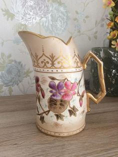 a ceramic pitcher with flowers painted on it