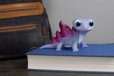 a small toy dragon sitting on top of a book