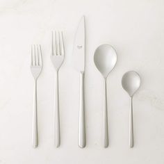 four forks, two spoons and one knife on a white surface