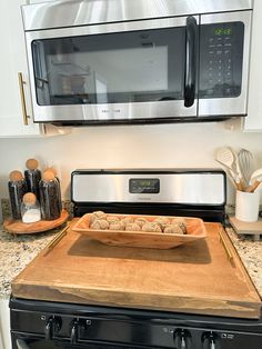 a pan of food sitting on top of a wooden cutting board in front of an oven