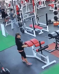 a woman is doing squats in the gym with red and black dumbbells