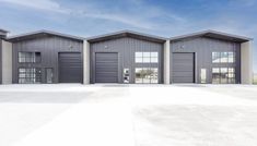 three garages with doors open in an empty lot