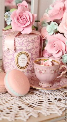 pink roses and teacups are sitting on a table next to the eiffel tower