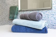 three towels stacked on top of each other in front of a bathroom mirror with blue and white wallpaper