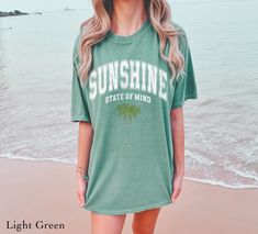 Sunshine State Of Mind With Palm Trees Trendy Graphic Tee. Design is intentionally distressed for a vintage look. SIZING & MATERIALS: Printed on Unisex Comfort Colors c1717 garment-dyed t-shirt for a relaxed fit; the fabric brings extra coziness to your wardrobe while the relaxed fit makes it an excellent daily choice.  .: 100% ring-spun cotton .: Medium fabric (6.1 oz/yd² (206.8 g/m *Sizing up 1-2 sizes gives an oversized look* Please compare measurements against our size chart for your perfect Summer Distressed Green Tops, Washed Short Sleeve Tops For Beach, Washed Short Sleeve Tops For The Beach, Beach-style Short Sleeve Washed Tops, Sunshine State Of Mind, Graphic Tee Vintage, Summer Graphic Tee, Trendy Graphic Tees, Beach Shirt