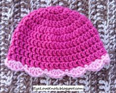 a crocheted pink and white hat sitting on top of a knitted blanket