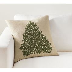 a christmas tree pillow sitting on top of a white couch