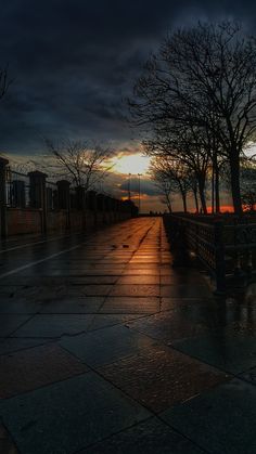 the sun is setting behind some trees and benches