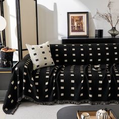 a black and white couch in a living room next to a table with two vases on it