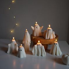 some white candles are sitting on a table with ghost figures in front of the candles