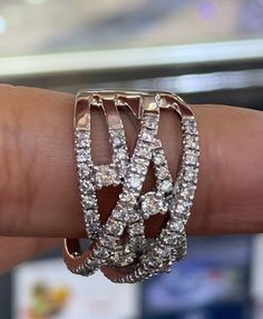 a woman's hand holding two rings with diamonds on it and the ring is made out of gold