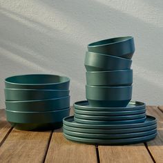 there are many bowls and plates stacked on the wooden table together, one is blue