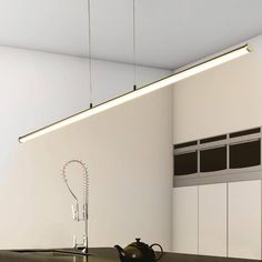 a kitchen with a kettle on the counter and lights hanging from the ceiling above it