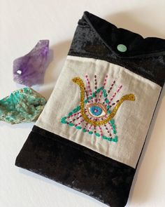 an embroidered pouch sitting on top of a table next to a rock and some crystals