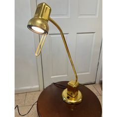 a gold desk lamp sitting on top of a wooden table next to a white door