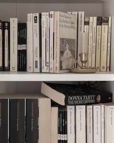 a book shelf filled with lots of books next to a candle on top of it