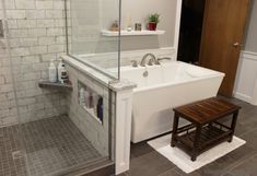 a white bath tub sitting next to a wooden bench in a bathroom under a window