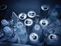 an assortment of sodas and water bottles sitting on top of a table next to each other