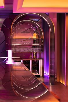 the interior of a modern bar with purple lighting and an arched glass door that leads to another room