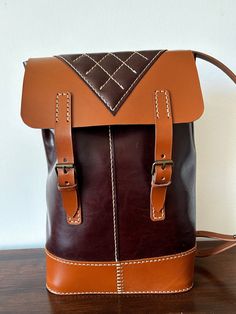 This is an unique item. Beautiful hand sewn leather backpack. The colour of the main bag is dark - a bit marbled - brown. The bottom, flap and straps are the colour cognac. The bottom, flap and straps are natural veg tan leather. The body is softer and a little thinner leather. Buckle closure.  The backpack has one inside pocket behind the quilted piece at the back. Width: 23 cm / 9 in Height: 35 cm / 13.5 in The bag will be sent as standard air mail with Danish courier PostNord with no tracking Everyday Cognac Backpack With Leather Lining, Daily Use Standard Backpack In Cognac, Cognac Leather Backpack, Vintage Brown Backpack With Leather Lining, Brown Leather Lined Backpack For Travel, Brown Vintage Backpack With Leather Lining, Cognac Backpack With Adjustable Strap For Travel, Travel Brown Leather Lined Backpack, Cognac Leather Daily Backpack With Leather Lining