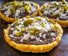 three small pizzas with cheese and green peppers on top are sitting on a table