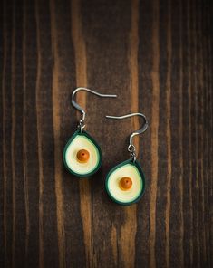 an avocado shaped earrings on a wooden surface