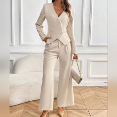 a woman standing in front of a white couch wearing a beige suit and matching heels