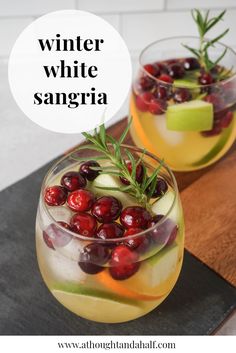 two glasses filled with drinks and garnished with cranberries, apples, and rosemary