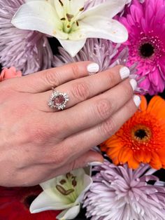 a woman's hand with an engagement ring on her finger surrounded by colorful flowers