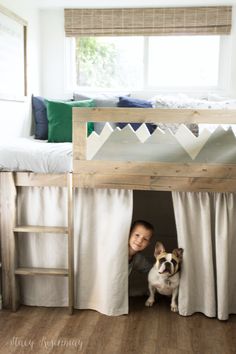 a young boy and his dog are peeking out from the bottom bunk of their bed