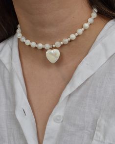 Pretty choker necklace handcrafted with real mother of pearl beads and an adorable heart pendant. Includes a 3" extender chain. MATERIALS. Mother of pearl (4mm and 8mm round beads, 20mm heart) 14k gold filled hardware Lobster clasp with 3" extender chain Model wearing 14" What is mother of pearl? Technically termed "nacre", it is the iridescent inner lining of certain mollusk shells. It is also the material that pearls are composed of.  PLEASE NOTE. Natural materials like freshwater pearls and g Pretty Choker Necklace, Y2k Coquette, Soft Girl Aesthetic, Pearl Heart, Pendant Choker, Soft Girl, Pearl Beads, Round Beads, Heart Pendant