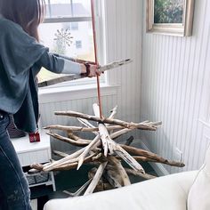 a woman standing in front of a christmas tree made out of sticks and branches,