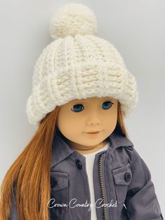 a doll with long hair wearing a white knitted beanie hat and gray jacket