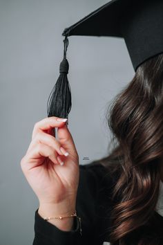 a woman wearing a graduation cap and gown holds her hand up to the side while she is holding a tassel