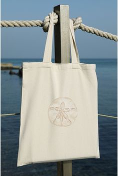 "This coastal canvas tote bag is ready for a trip to the beach. Whether you're heading to the beach, strolling through a farmer's market, or simply running errands around town, this tote bag is your ideal companion. This Sand Dollar Cotton Canvas Tote Bag is the perfect blend of coastal charm with a trendy tan design.  🐚 Design: The Sand Dollar Tote Bag features a neutral watercolor painting that evokes the calmness of a morning by the beach. Its intricate sand dollar pattern, rendered in soft, Neutral Watercolor, Cactus Art Print, Tote Beach Bag, Tote Bag Beach, Beach Lover Gifts, Painted Tote, Sand Bag, Embroidered Tote, Eco Friendly Bags