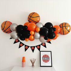 an arrangement of balloons and basketballs on a wall