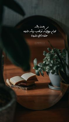 an open book sitting on top of a wooden table next to a potted plant