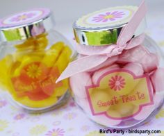 two glass jars filled with candies on top of a flowery tablecloth covered table