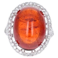 This beautiful ring has a 26.12 carat Cabochon Spessartine set in the center of the ring. A Spessartine is a natural stone that is actually a part of the Garnet family of stones. The ring is surrounded by 52 Round Brilliant Cut Diamonds that weigh 0.85 carats. The total carat weight of the ring is 26.97 carats. This ring is 14K White Gold and weighs approximately 7.5 grams. The ring is a size 6.75 and can be re-sized at no additional charge. Garnet And Diamond Ring, Eternal Beauty, Vintage Cocktail Ring, Gold Cocktail Ring, Contemporary Ring, Gold Cocktail, Natural Amber, Vintage Cocktail, Modern Ring