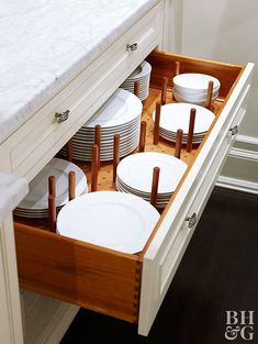 an open drawer in a kitchen filled with plates