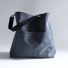 Our black hobo bag has a relaxed, casual style in a durable canvas with a subtle stone-washed (heathered) finish.  Stay organized with plenty of pockets inside and two large pockets outside.   The wide leather strap options allow for a comfortable carry as a shoulder bag or crossbody bag. This listing is for the Large size in Dark Charcoal Sun-washed Canvas. Details: Approximately 15in W x 14.5in H x 3in D Exterior is cotton canvas in Dark Charcoal Gray with a subtle faded finish Fully lined Three interior slip pockets, one interior zipper pocket, two exterior large slip pockets Magnetic snap closure at top center Leather is sourced and dyed in the US. Natural Leather color option may darken to a tan patina over time. Black Hobo Bag, Canvas Bucket Bag, Large Hobo Bag, Hobo Bags, Black Tote, Hobo Handbags, Stay Organized, Black Tote Bag, Charcoal Gray