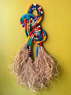 a wall hanging made out of different colored beads and rafters on a yellow wall